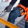 Construction worker use safety harness and safety line working on a new construction site project.