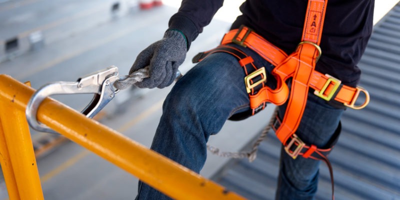 Construction worker use safety harness and safety line working on a new construction site project.